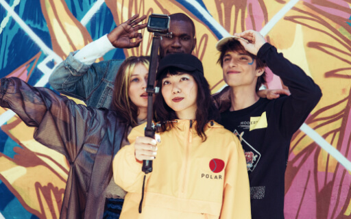 Friends wearing a yellow jacket, denim jacket, raincoat and black sweatshirt takes selfie pictures on the jungle motive background.